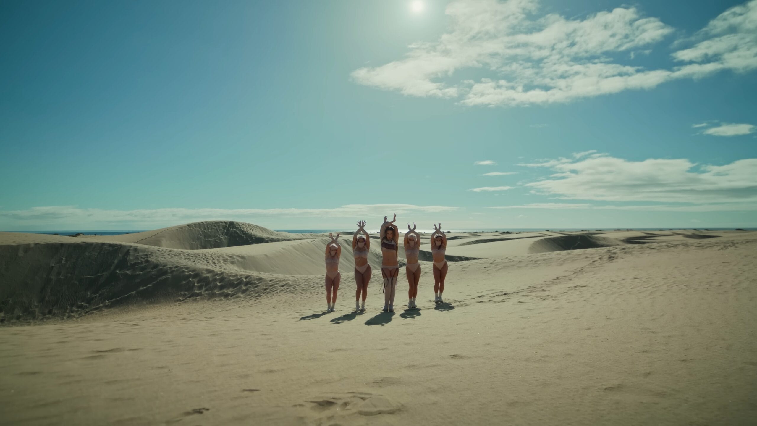 El tonto — A group of women in bikinis pose on a beach.