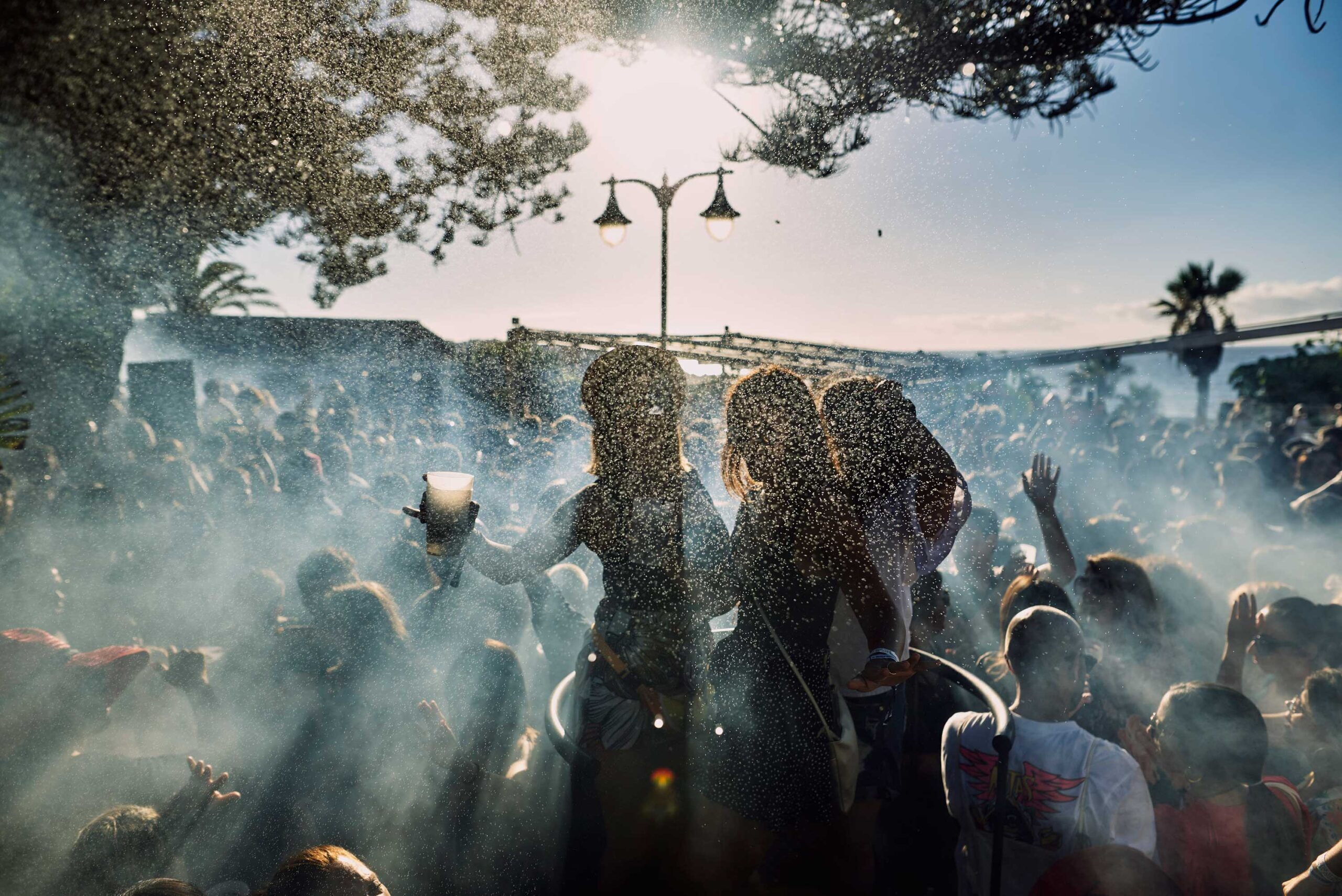 Brunch nuestro de cada dia — A group of people are standing in front of a light pole, with two girls in the center of the crowd.