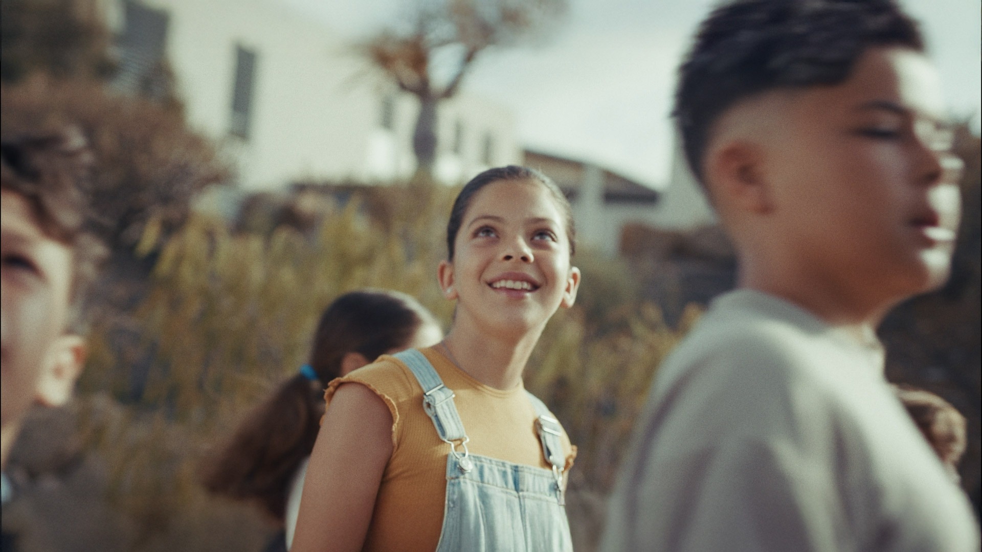 ITER 35 — A young girl wearing a yellow shirt and blue overalls is smiling.