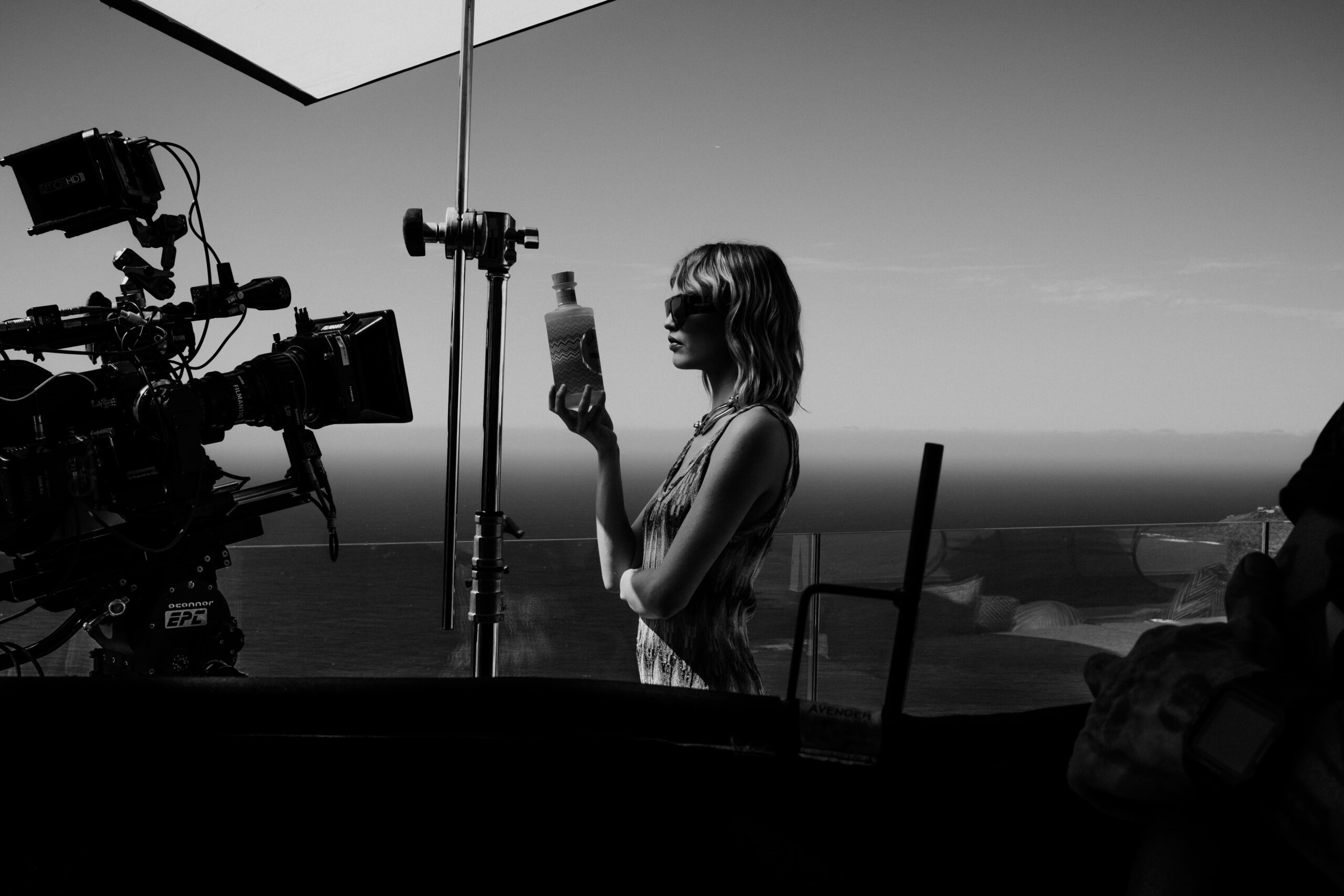 Malfy + Missoni — A woman holding a bottle of water in front of a camera.