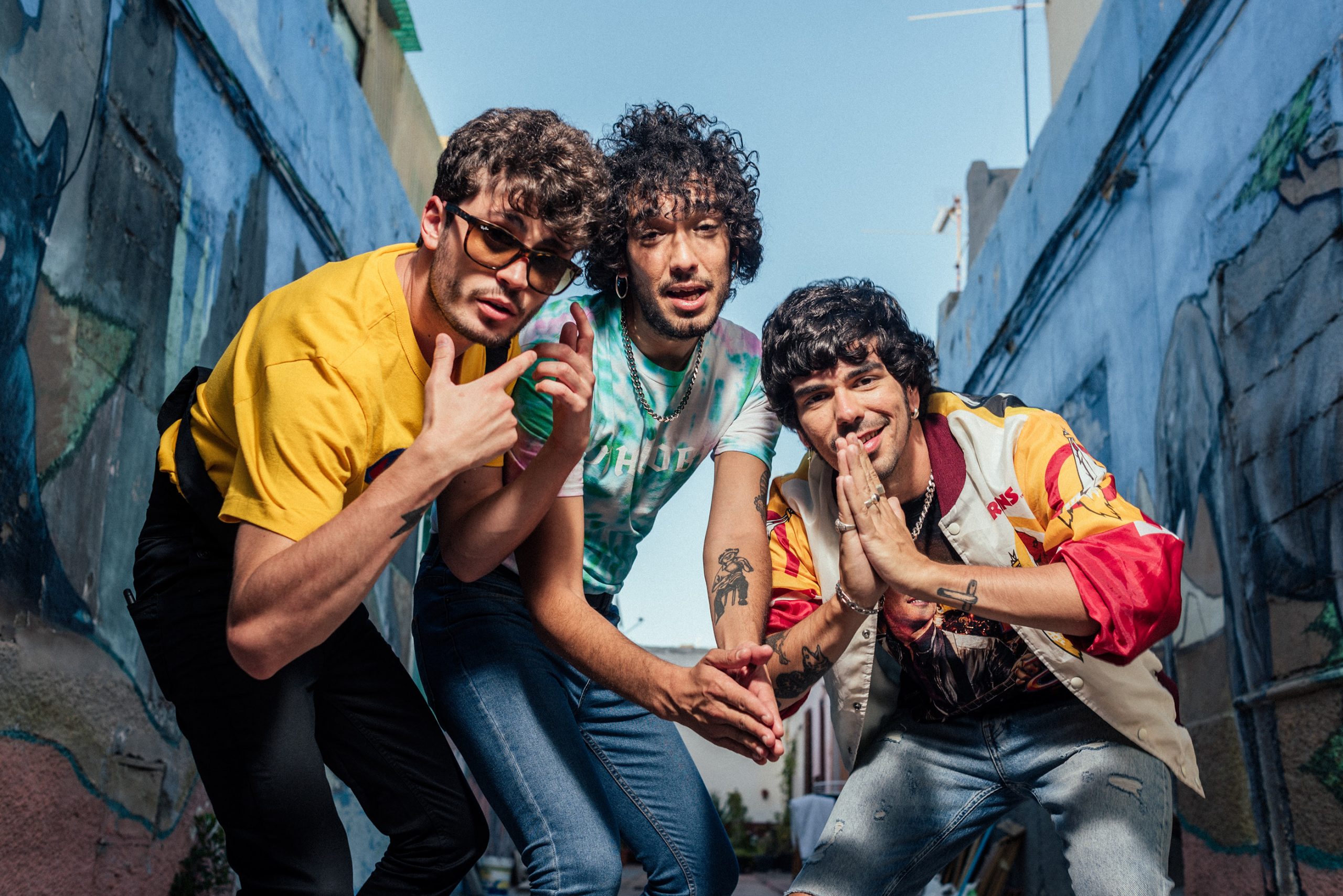 Pa que te quedes conmigo — Three men wearing sunglasses and colorful shirts pose together.
